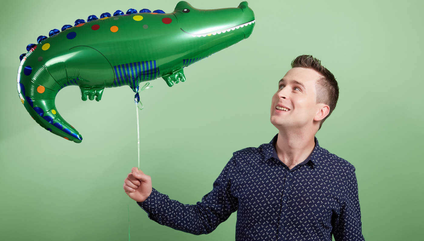 man holding a foil crocodile helium balloon
