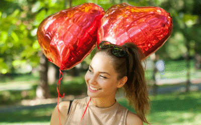 A woman holding two love balloons in a park