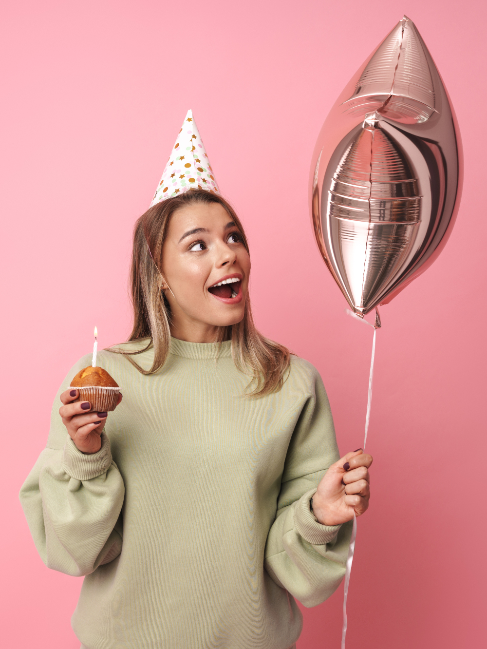 happy girl holding a cup cake and a rose gold star helium balloon